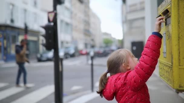 在法国巴黎的一条街上 一个可爱的学龄前女孩把信放在黄色的邮筒里 — 图库视频影像