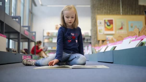 Urocza Przedszkolanka Siedząca Podłodze Bibliotece Miejskiej Czytająca Książkę — Wideo stockowe