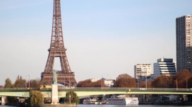 PARIS, FRANCE - 22 Kasım 2023: Paris, Fransa 'da aydınlık bir sonbahar gününde Grenelle köprüsü ve Özgürlük Heykeli ile Seine nehri üzerindeki Eyfel Kulesi