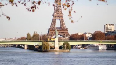 PARIS, FRANCE - 22 Kasım 2023: Paris, Fransa 'da aydınlık bir sonbahar gününde Grenelle köprüsü ve Özgürlük Heykeli ile Seine nehri üzerindeki Eyfel Kulesi