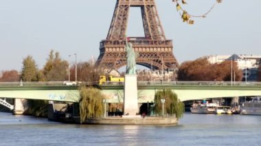 PARIS, FRANCE - 22 Kasım 2023: Paris, Fransa 'da aydınlık bir sonbahar gününde Grenelle köprüsü ve Özgürlük Heykeli ile Seine nehri üzerindeki Eyfel Kulesi