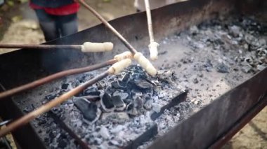 Çocuklar ormanda bir piknik sırasında kamp ateşinde çubukların üzerinde kızarmış ekmek pişiriyorlar. Çocuklar için açık hava aktiviteleri