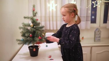 Küçük Noel ağacını evde minyatür oyuncaklarla süsleyen sevimli anaokulu kızı. Noel ve Yeni Yıl Bekleyen Çocuk