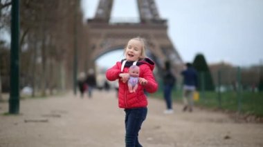 Paris, Fransa 'daki Eyfel Kulesi' nin önünde oyuncak bebeği olan sevimli anaokulu kızı.