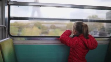 Paris yeraltı treniyle seyahat eden ve Eyfel Kulesi, Paris, Fransa 'nın penceresinden bakan sevimli anaokulu kızı.