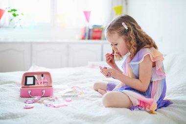 Tek boynuzlu at tüyü süslemeli, çocuklarla oynayan ve makyaj yapan tatlı anaokulu kızı.