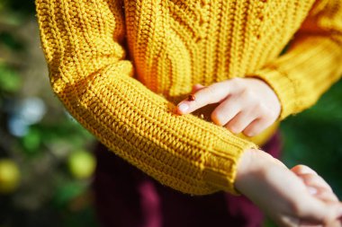Anaokulu kızı, uğurböceğine bakıyor. Ellerinde ve parmaklarında sürünüyor.