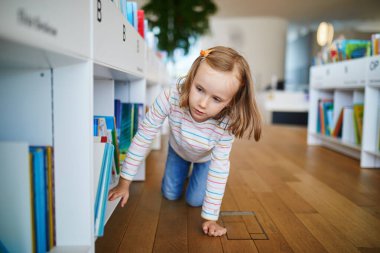 Belediye kütüphanesinde kitap seçen beş yaşında bir kız..