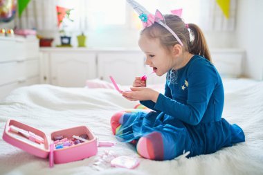 Tek boynuzlu at tüyü süslemeli, çocuklarla oynayan ve makyaj yapan tatlı anaokulu kızı.