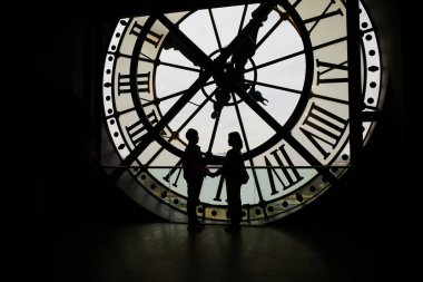 Paris, Fransa 'da, büyük saatin önünde romantik bir çift duruyor. Paris 'e tepeden bakan tanınmayan insanlar..