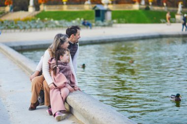 Üç kişilik mutlu bir aile, baba, anne ve kız Lüksemburg 'un Paris bahçesinde birlikte vakit geçiriyorlar.