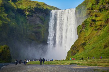 SKOGAFOSS, ICELAND - 15 Temmuz 2024: İzlanda 'nın en büyük şelalelerinden biri olan Skogafoss' un manzarasının tadını çıkaran pek çok turist