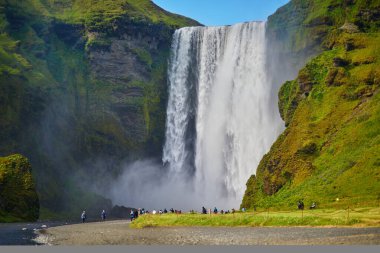 SKOGAFOSS, ICELAND - JULY 15, 2024: Lots of tourists enjoying scenic view of Skogafoss, one of the biggest waterfalls of Iceland clipart