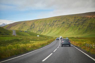 Car driving on a road surrounded by beautiful landscape in Iceland clipart