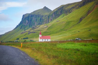 Güney İzlanda 'da buzlu ve karlı görkemli uçurumların yanında kırmızı çatıları olan güzel evler.