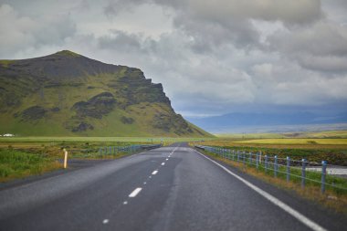 Yeşil tarlaları olan güzel doğa manzarası ve Güney İzlanda 'da buzlu ve karlı görkemli uçurumlar.