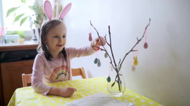 Paskalya için evi dekore eden sevimli anaokulu kızı. Çocuk Paskalya kutlaması için hazırlanıyor. Aile gelenekleri.