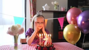 Mutlu küçük kız yedinci yaş gününü kutluyor ve bir dilek tutuyor. Doğum günü pastası ve mumu olan küçük çocuk..