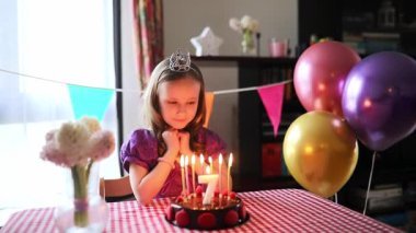 Mutlu küçük kız yedinci yaş gününü kutluyor ve bir dilek tutuyor. Doğum günü pastası ve mumu olan küçük çocuk..