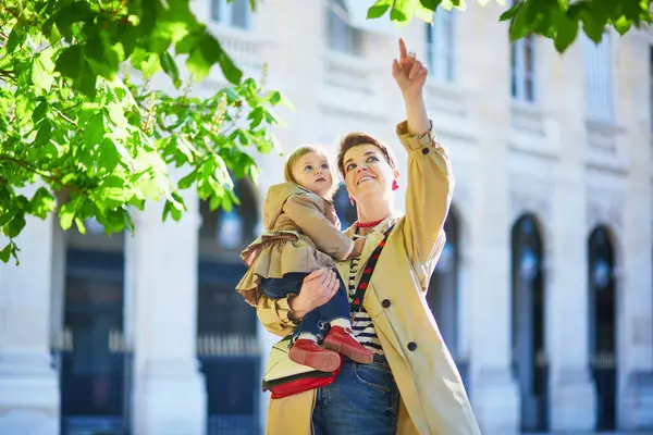 Güzel genç anne ve tapılası küçük kızı Paris, Fransa 'da parkta birlikte yürüyorlar.