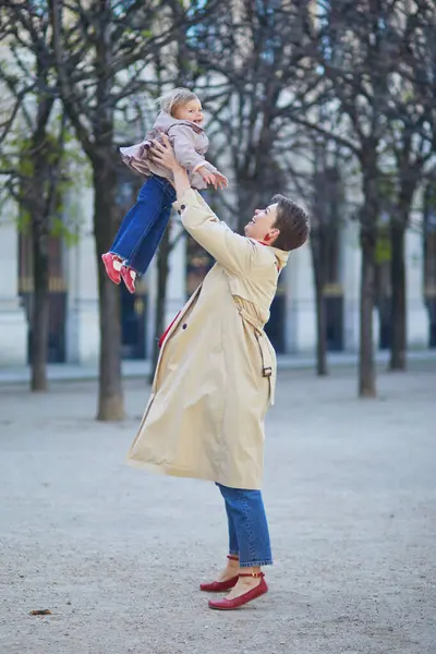 Güzel genç anne ve tapılası küçük kızı Paris, Fransa 'da parkta birlikte yürüyorlar.