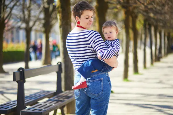 Güzel genç anne ve tapılası küçük kızı Paris, Fransa 'da parkta birlikte yürüyorlar.