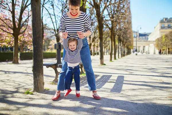 Güzel genç anne ve tapılası küçük kızı Paris, Fransa 'da parkta birlikte yürüyorlar.