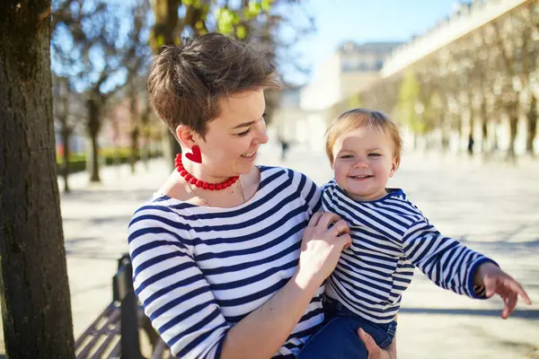 Güzel genç anne ve tapılası küçük kızı Paris, Fransa 'da parkta birlikte yürüyorlar.