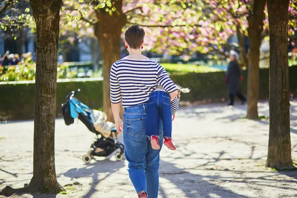 Güzel genç anne ve tapılası küçük kızı Paris, Fransa 'da parkta birlikte yürüyorlar.