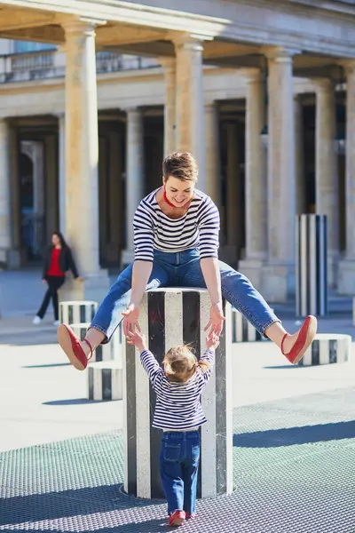 Güzel genç anne ve tapılası küçük kızı Paris, Fransa 'da parkta birlikte yürüyorlar.