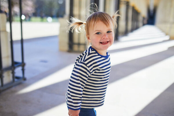 Adorable toddler girl walking in a park in Paris, France.