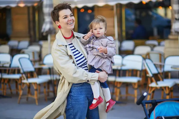 Güzel genç anne ve tatlı küçük kızı Paris, Fransa 'daki açık kafede eğleniyorlar.