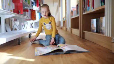 Belediye kütüphanesinde yerde oturmuş kitap okuyan sevimli liseli kız..