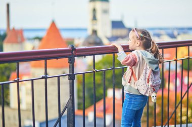 Sırt çantalı sevimli anaokulu kızı Estonya 'nın Tallinn şehrinin eski manzarasının tadını çıkarıyor.