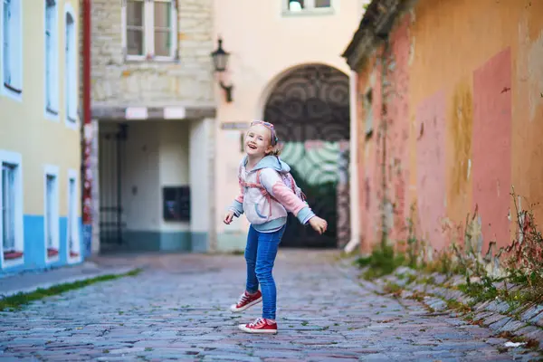 Sevimli anaokulu kızı Tallinn, Estonya 'da bir sokakta eğleniyor.