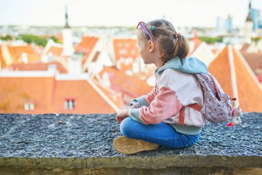 Sırt çantalı sevimli anaokulu kızı Estonya 'nın Tallinn şehrinin eski manzarasının tadını çıkarıyor.