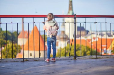 Sırt çantalı sevimli anaokulu kızı Estonya 'nın Tallinn şehrinin eski manzarasının tadını çıkarıyor.