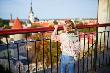 Sırt çantalı sevimli anaokulu kızı Estonya 'nın Tallinn şehrinin eski manzarasının tadını çıkarıyor.