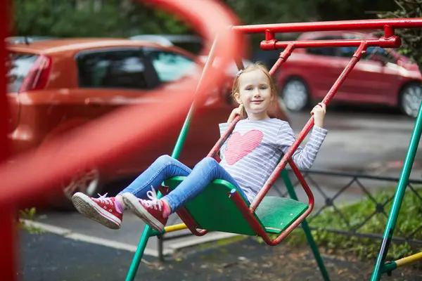 Mutlu 6 yaşındaki kız salıncakta sallanıyor. Oyun bahçesinde tahterevallide sallanan mutlu çocuk. Çocuklar için açık hava yaz etkinlikleri