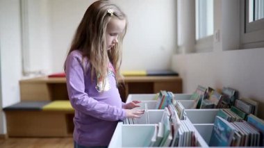 Belediye kütüphanesinde kitap seçen sevimli liseli kız.