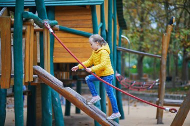 Neşeli küçük kız Paris, Fransa 'daki sonbahar parkında oyun alanında eğleniyor.