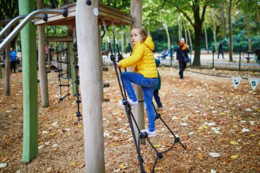 Neşeli küçük kız Paris, Fransa 'daki sonbahar parkında oyun alanında eğleniyor.
