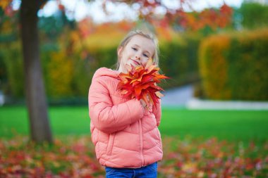 Neşeli küçük kız Paris, Fransa 'daki sonbahar parkında yürüyüşünün tadını çıkarıyor.