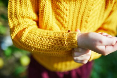 Anaokulu kızı, uğurböceğine bakıyor. Ellerinde ve parmaklarında sürünüyor.
