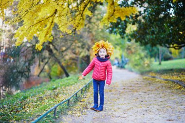 Akçaağaçlı sevimli anaokulu kızı dışarıda güzel ve güneşli bir sonbahar gününün tadını çıkarıyor. Mutlu çocuk Paris, Fransa 'da bir sonbahar gününde yürüyor