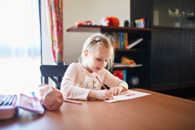 küçük kız ödevini evde yapıyor