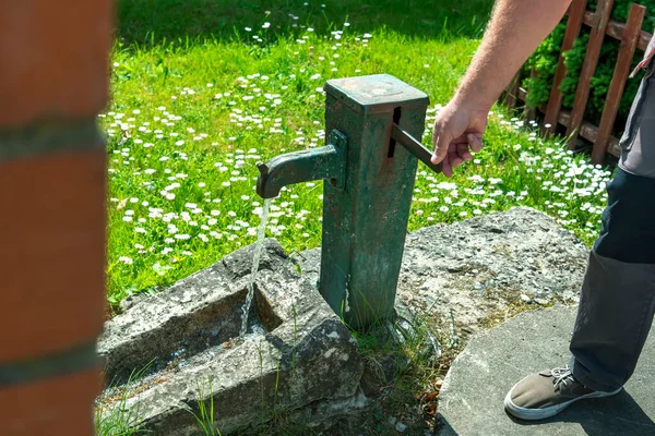 男は小さな町の裏庭の公共の水ポンプから水を汲み上げる — ストック写真
