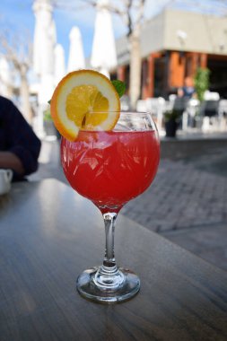 Kafenin dışındaki ahşap masada turuncu dilimli kırmızı kokteyl..