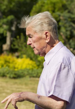 Evin arka bahçesinde yaşlı bir adamın portresi..