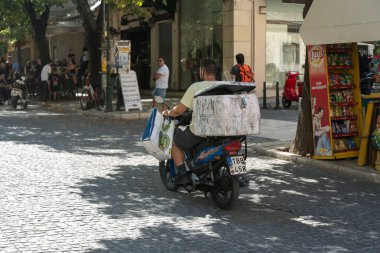 GREECE, CORFU - 8 Ağustos - Korfu veya Kerkyra Yunanistan 'ın İyon Adaları' nın Korfu adasında bir şehirdir. 21 Eylül 2021 'de motosikletli teslimatçının görüntüsü, Korfu, Yunanistan.